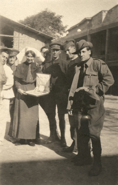 Marjorie surrounded by Australian soldiers as she holds a newly opened Christmas gift.